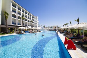Relax by the pool surrounded by lounge chairs and umbrellas, with stunning views of the adjacent building.