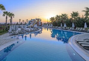 Relax by the serene pool surrounded by palm trees and sun loungers, with a water slide nearby for added fun.