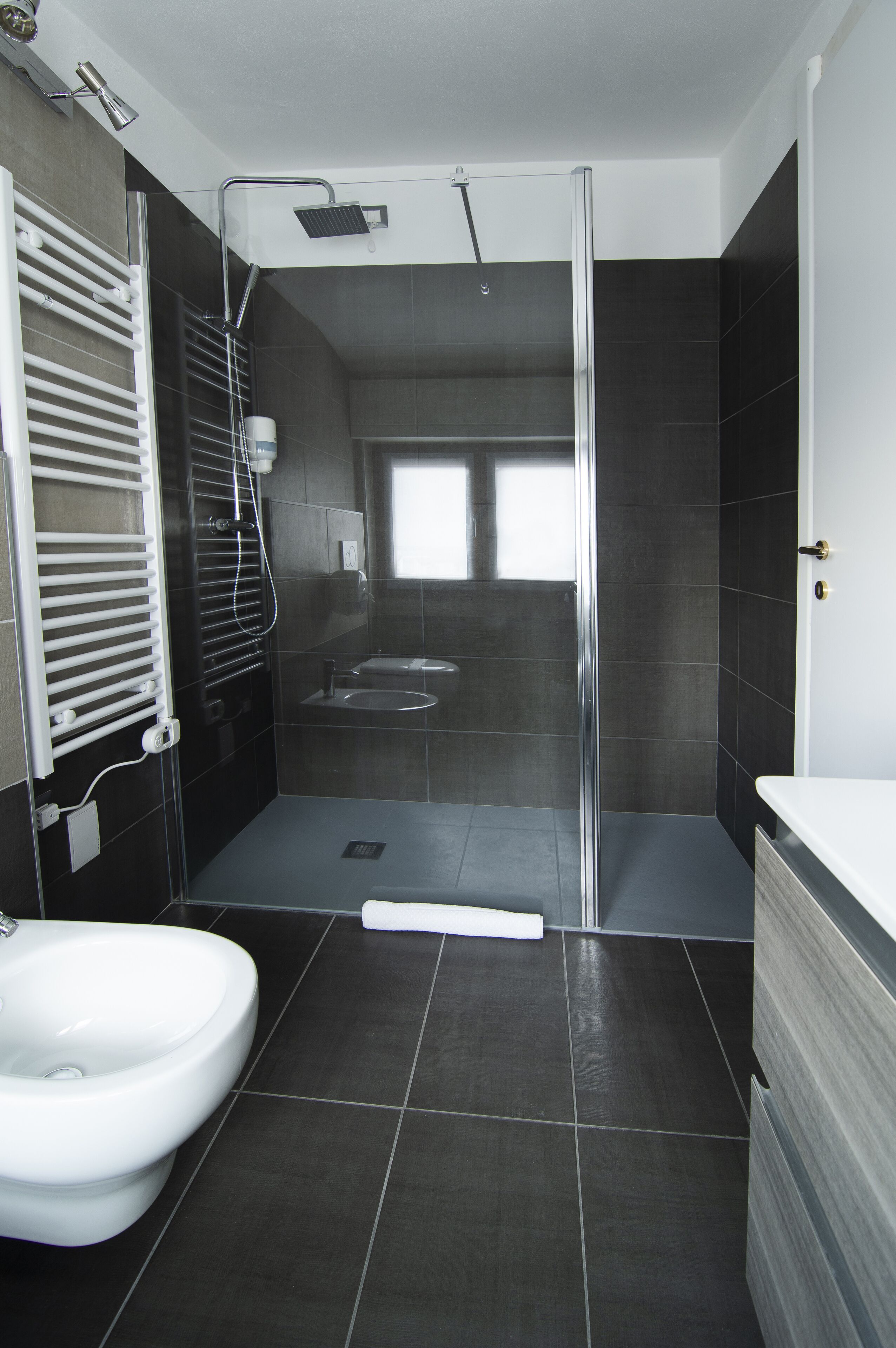Un bany modern amb dutxa amb envàs de vidre, un vàter blanc i un lavabo.