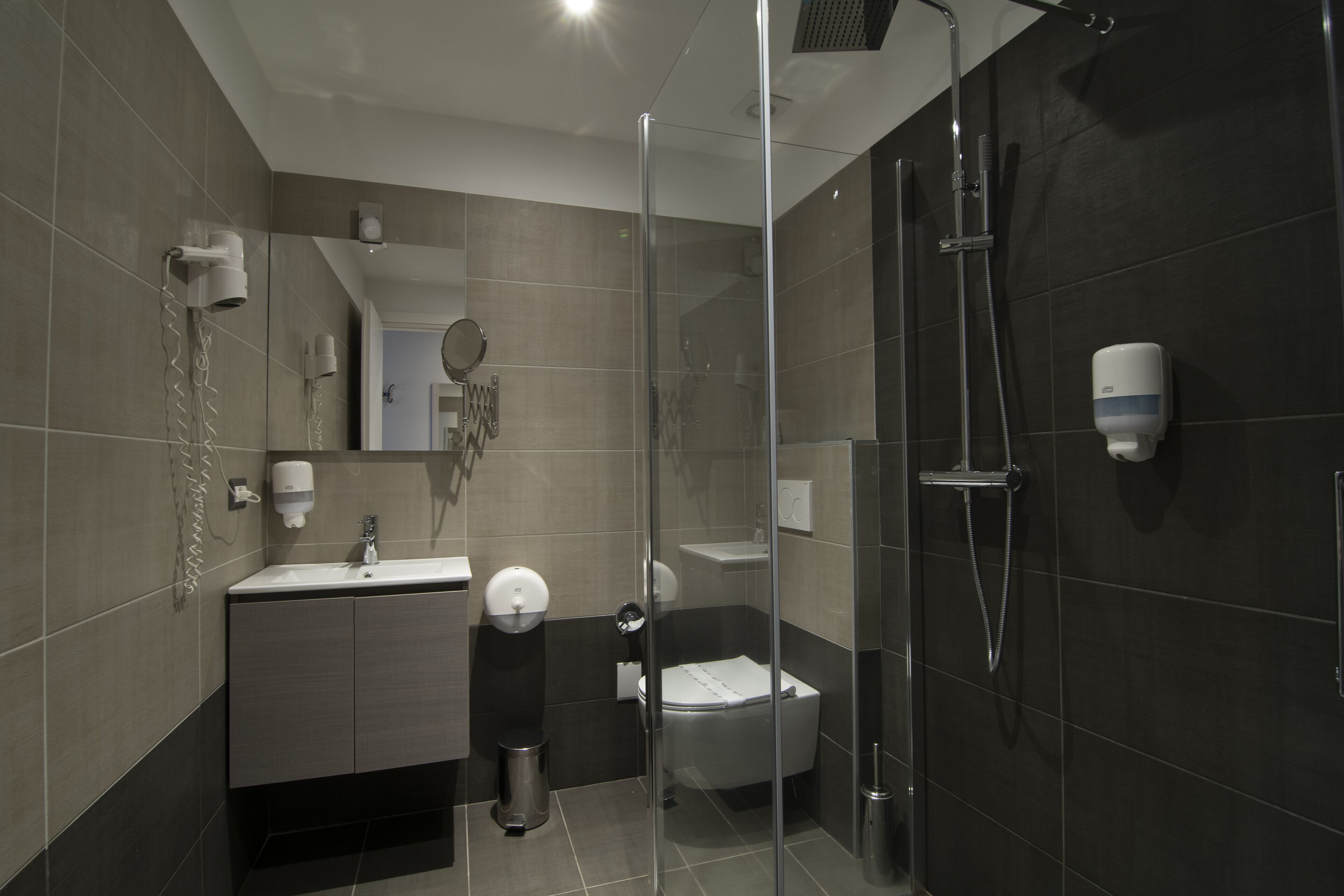 A modern bathroom with a glass-enclosed shower, a sink, and a toilet.