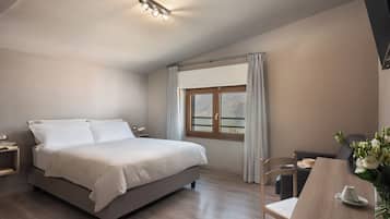 A bedroom with a bed, a desk, a chair, a window with curtains, and a ceiling light fixture.