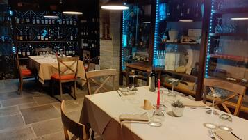 Un ristorante con tavoli apparecchiati, bottiglie di vino sugli scaffali e una parete in pietra.