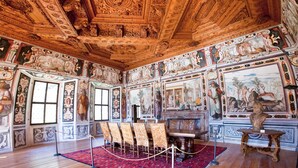Une pièce dotée d’un plafond et de murs richement décorés, d’une cheminée et d’un tapis rouge.