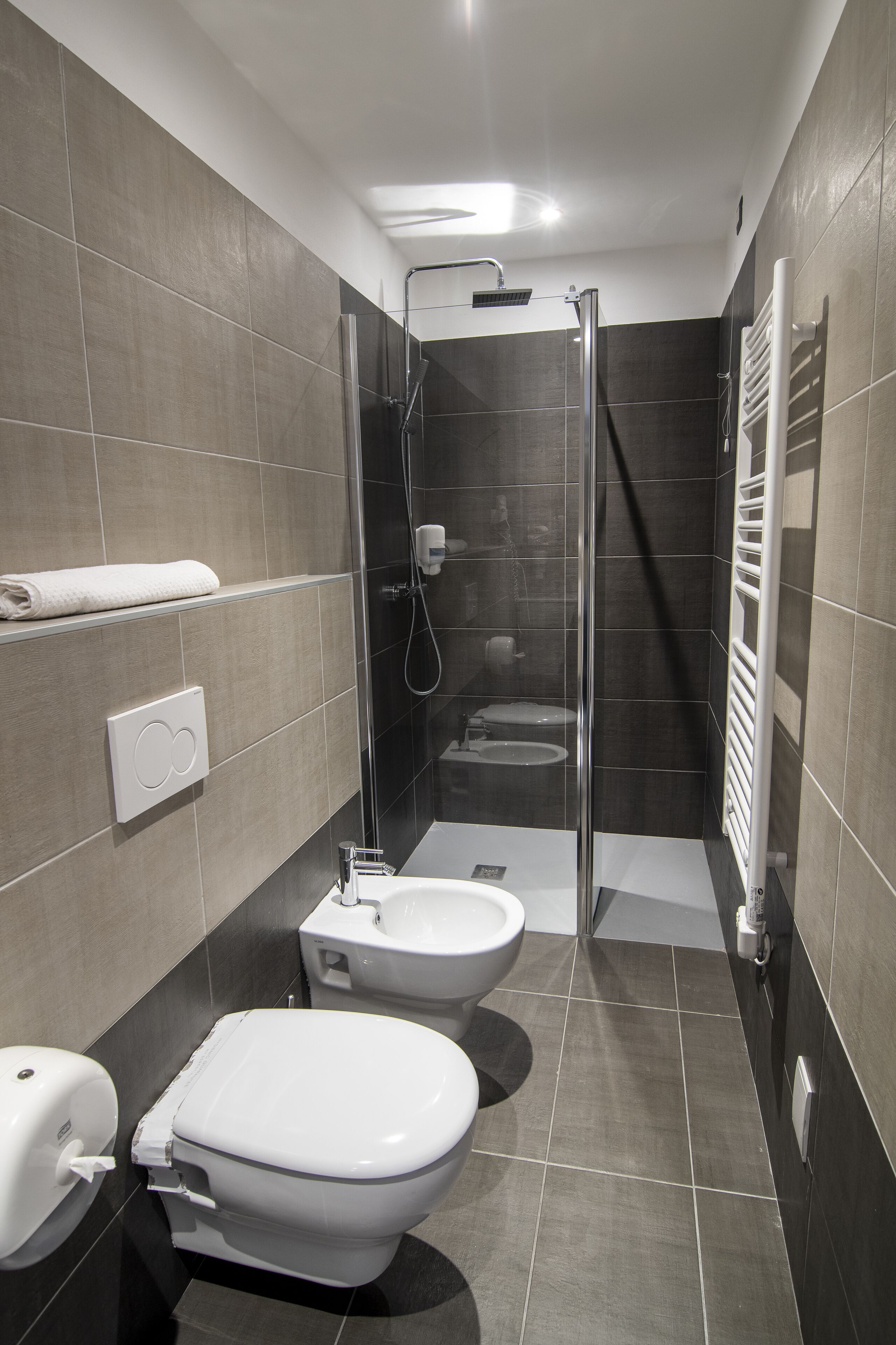A modern bathroom with a shower, toilet, and bidet.