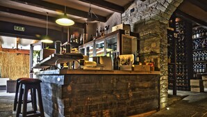 Un espace bar avec un comptoir en bois, des tabourets et un mur en pierre.