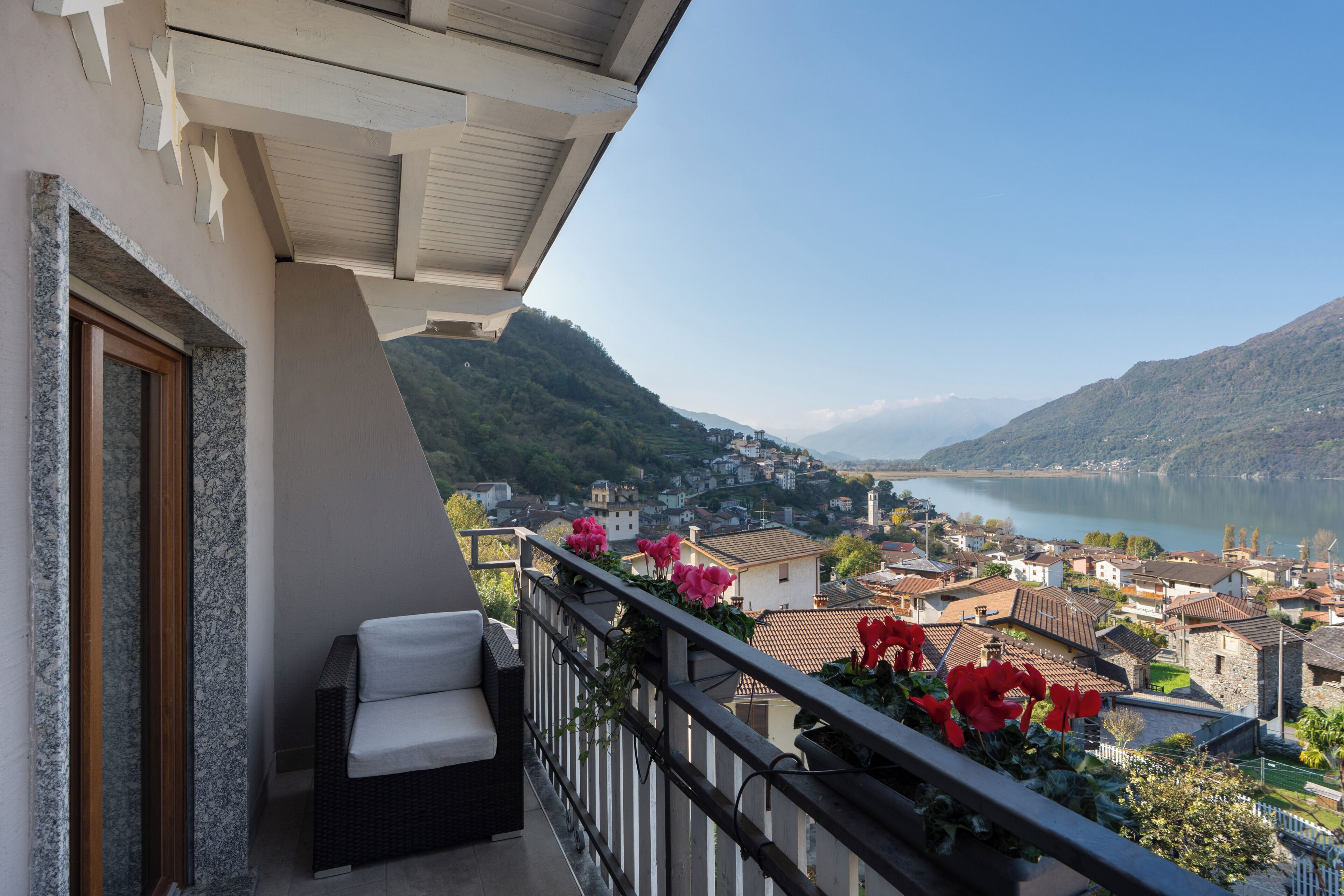 Un balcon avec un fauteuil en osier et une vue sur un lac et la ville.