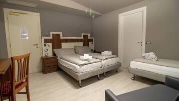 A bedroom with a bed, a chair, a bedside table, and a small desk.