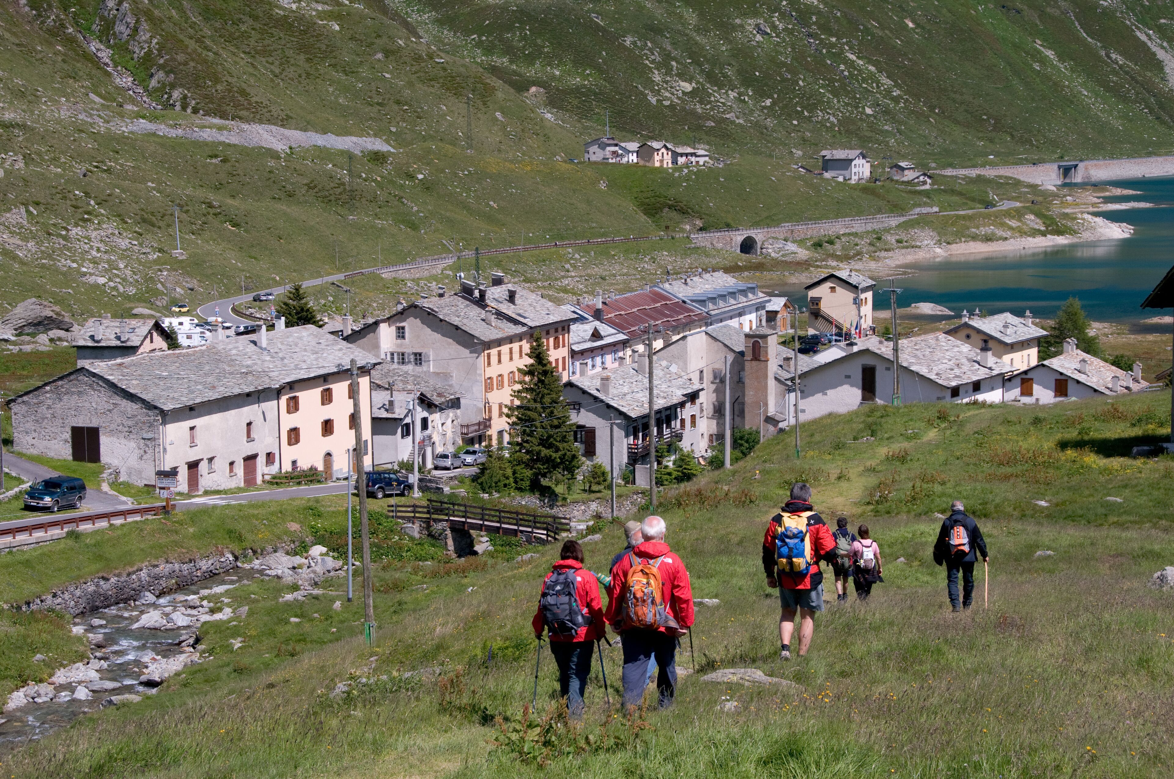 A group of hikers on a mountain trail with a small village in the background.