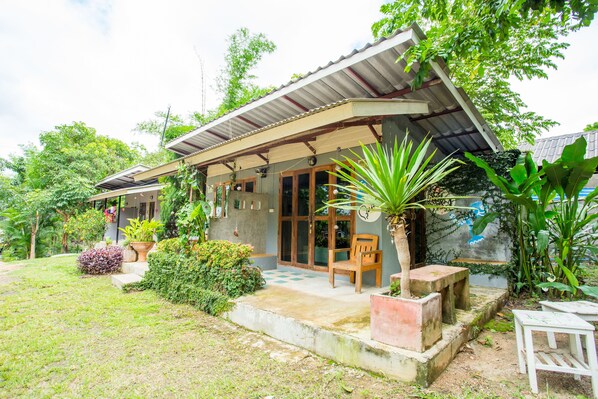 A house with a covered porch, a small garden, and a wooden chair.