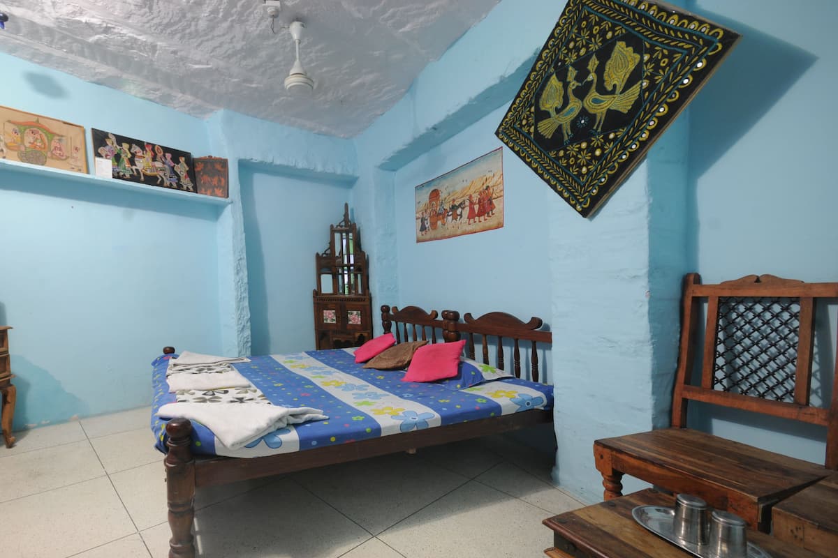 A bedroom with a bed, a wooden nightstand, a television, and a decorative wall hanging.