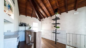 A modern kitchen with a wooden ceiling, white cabinetry, and a central island with bar stools. - La corte sul naviglio (Boffalora Sopra Ticino)