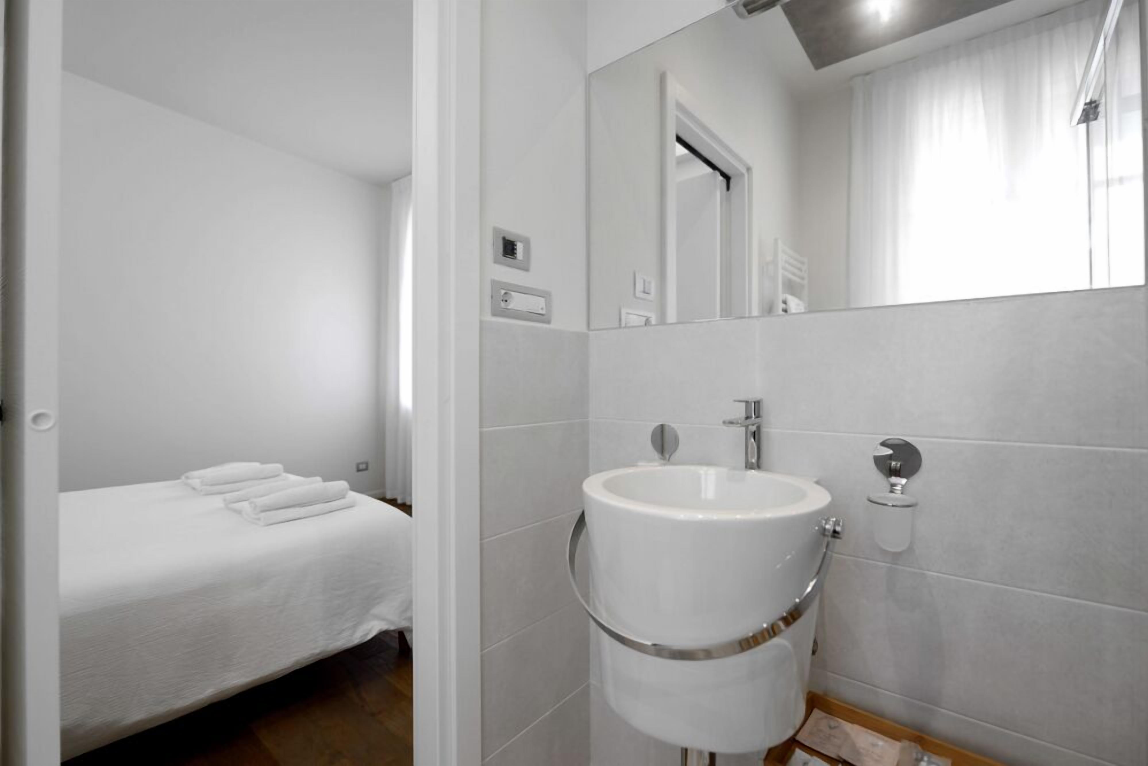 Een hotelkamer met een bed, een wit wastafel en een spiegel.