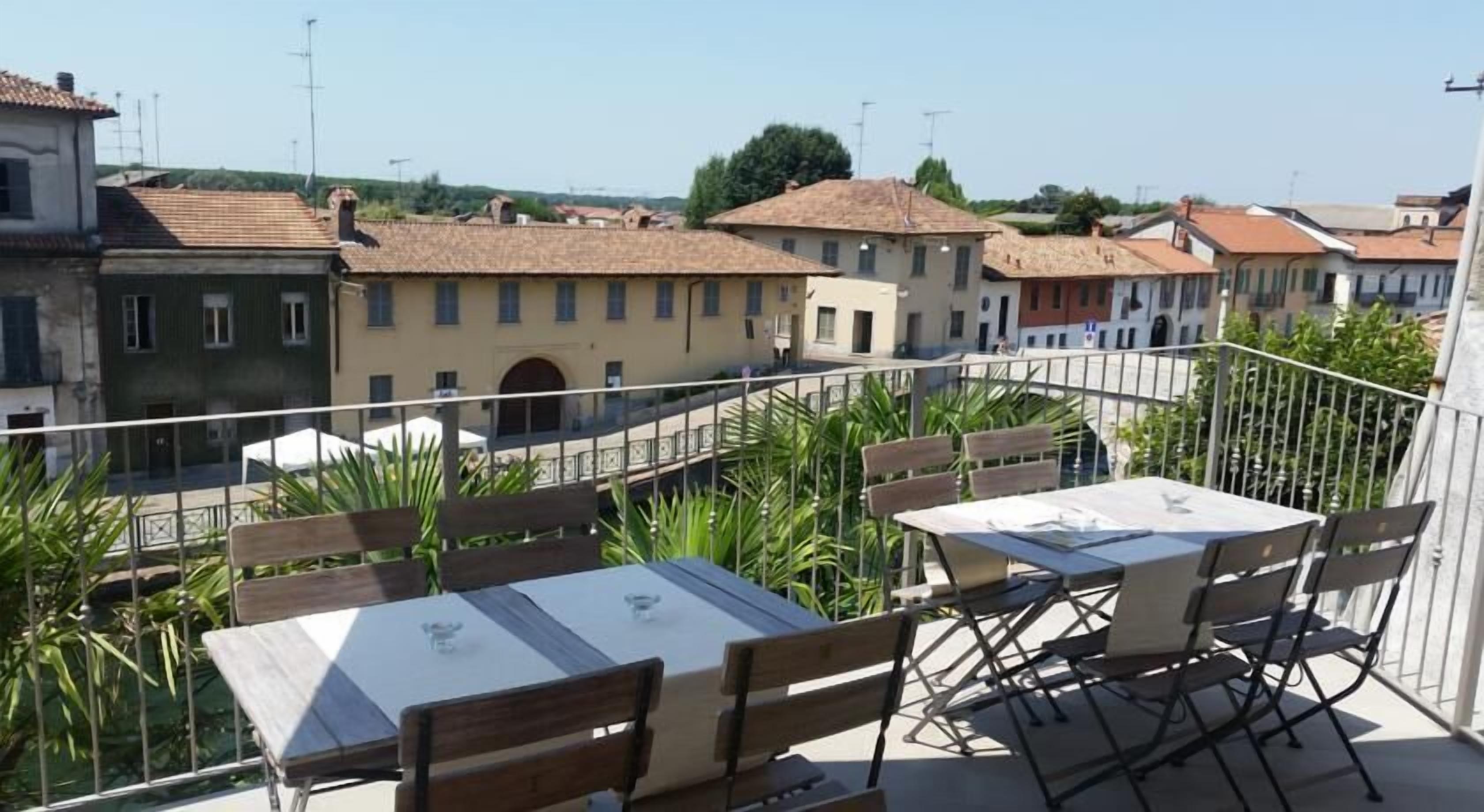 Eine Terrasse mit Tischen und Stühlen, mit Blick auf eine Stadt mit traditioneller Architektur.