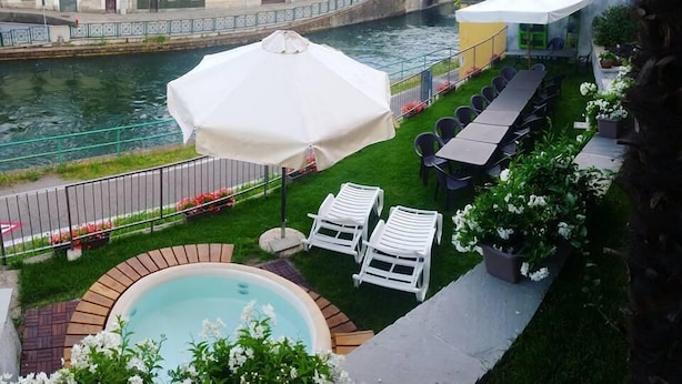 A rooftop terrace with a pool, outdoor seating, and a view of a canal with buildings. - La corte sul naviglio (Boffalora Sopra Ticino)