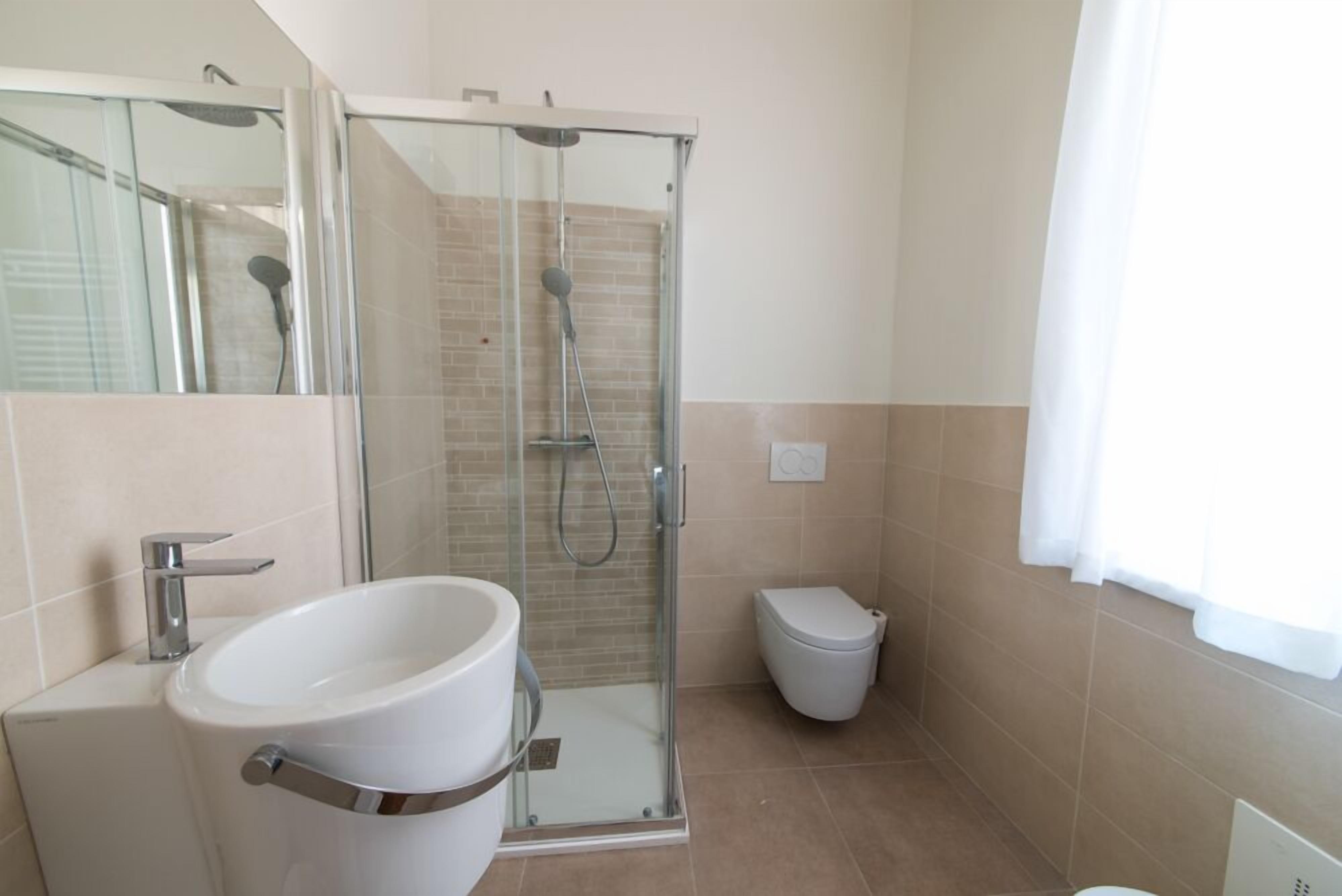 Ein modernes Badezimmer mit einer Glasdusche, einem weißen Waschbecken und einer Toilette.