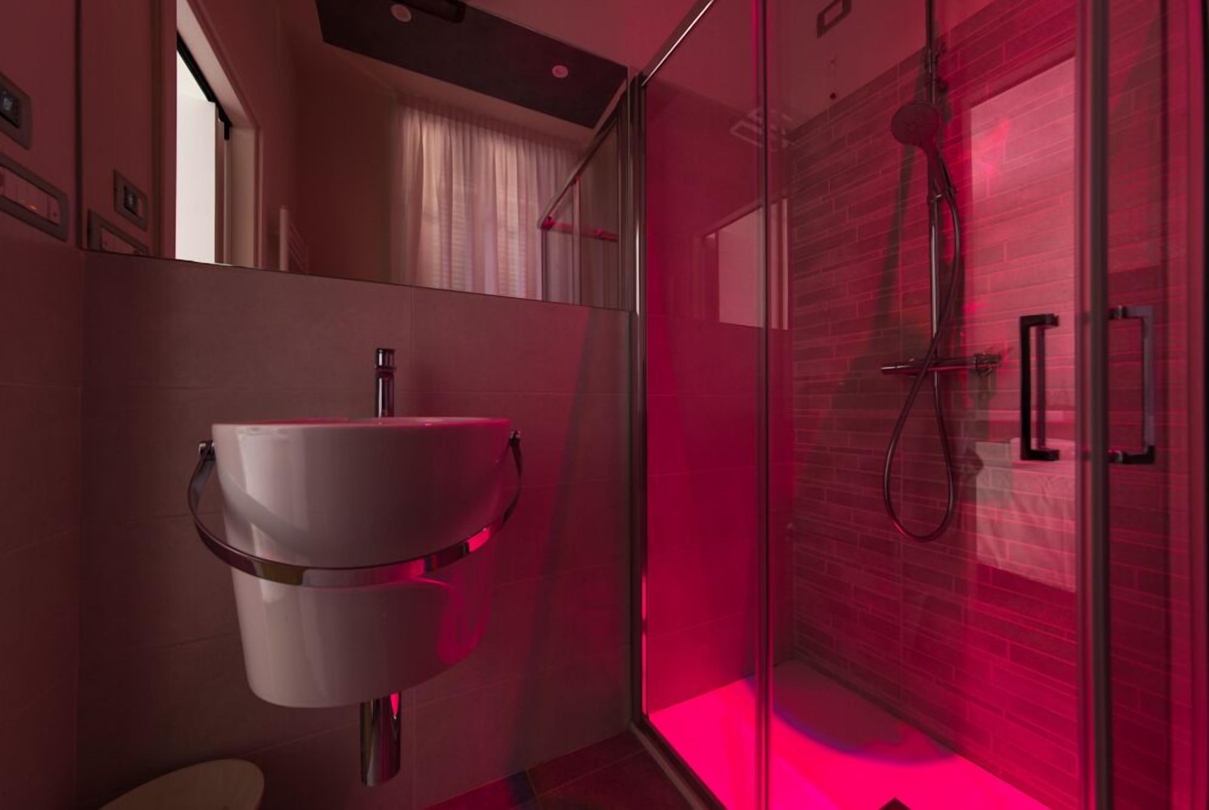 Een moderne badkamer met een douchecabine van glas, een witte wastafel en een zichtbaar toilet.