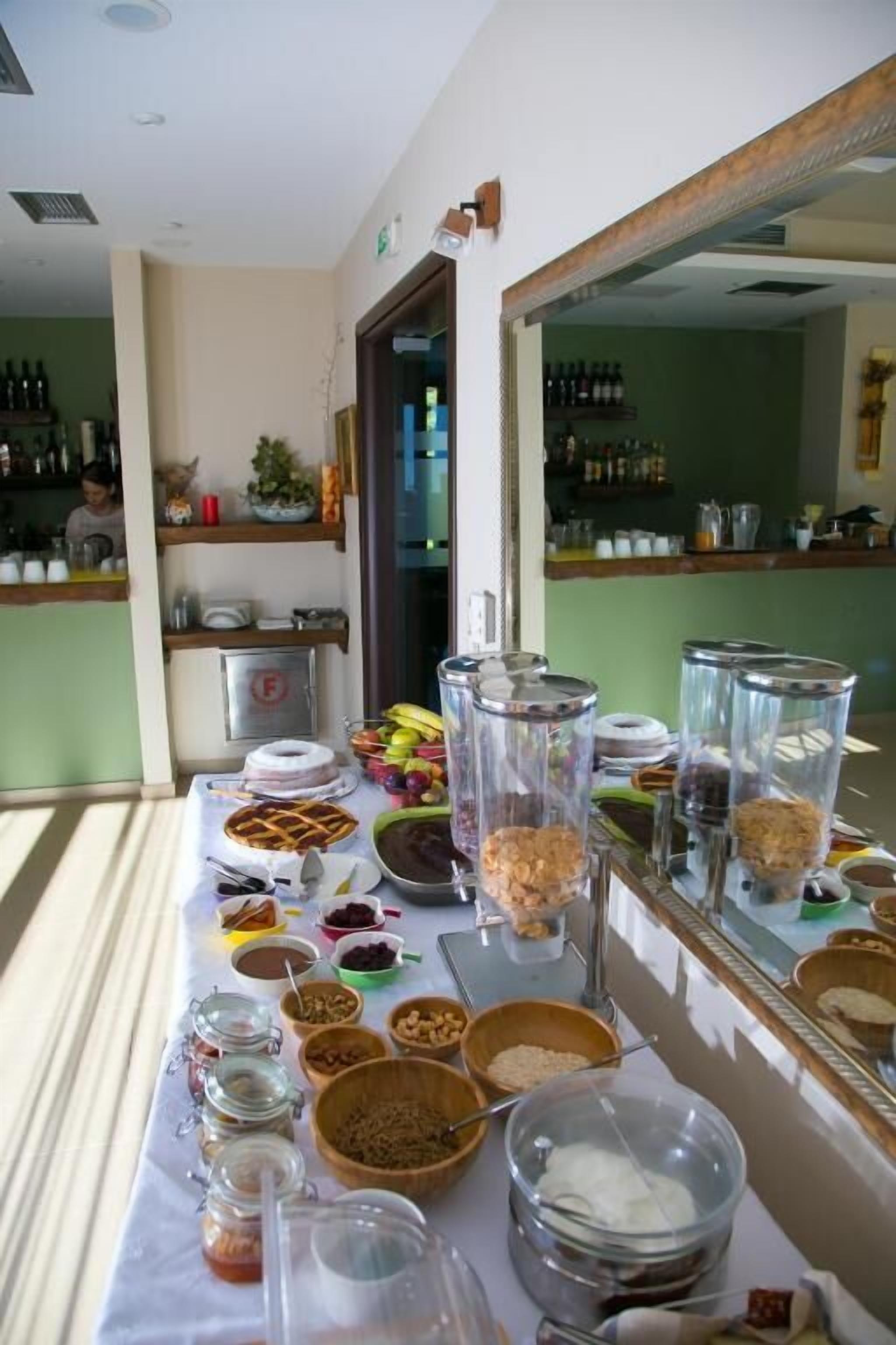 A buffet table with various food items and containers, a mirror reflecting the room, and shelves with bottles in the background.