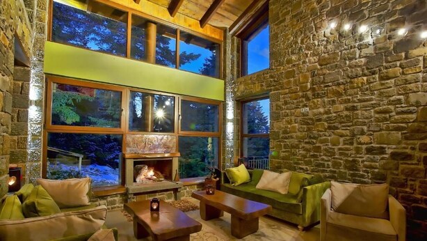 A cozy interior with stone walls, a fireplace, and large windows overlooking a snowy landscape. - Anavasi Mountain Resort (North Tzoumerka)