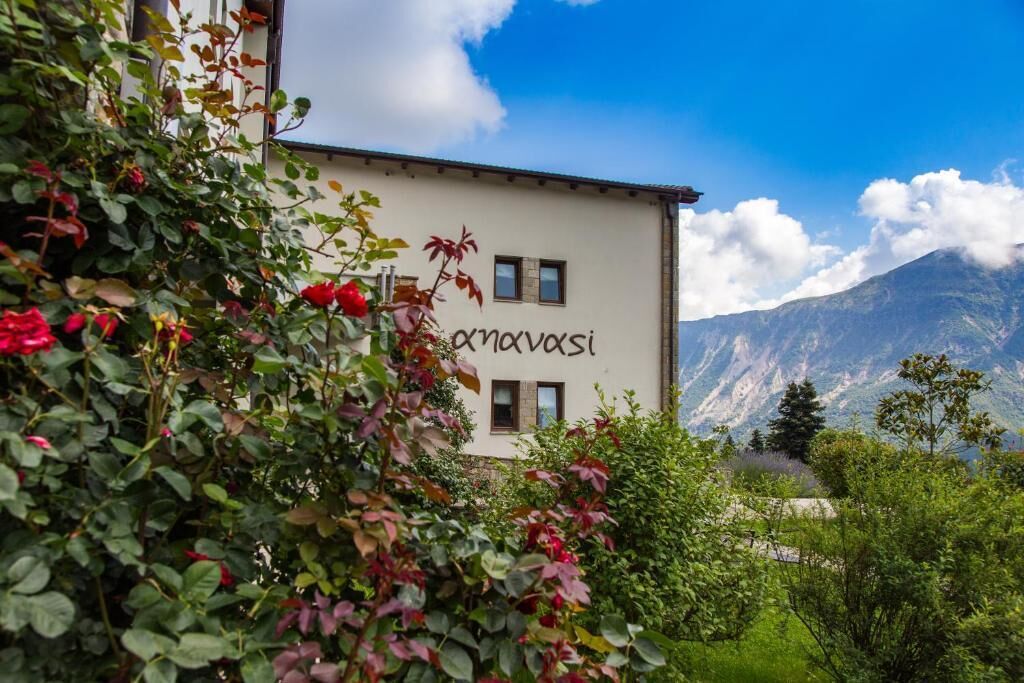 A building with the name "novosisi" on its facade, surrounded by lush greenery and mountains in the background.