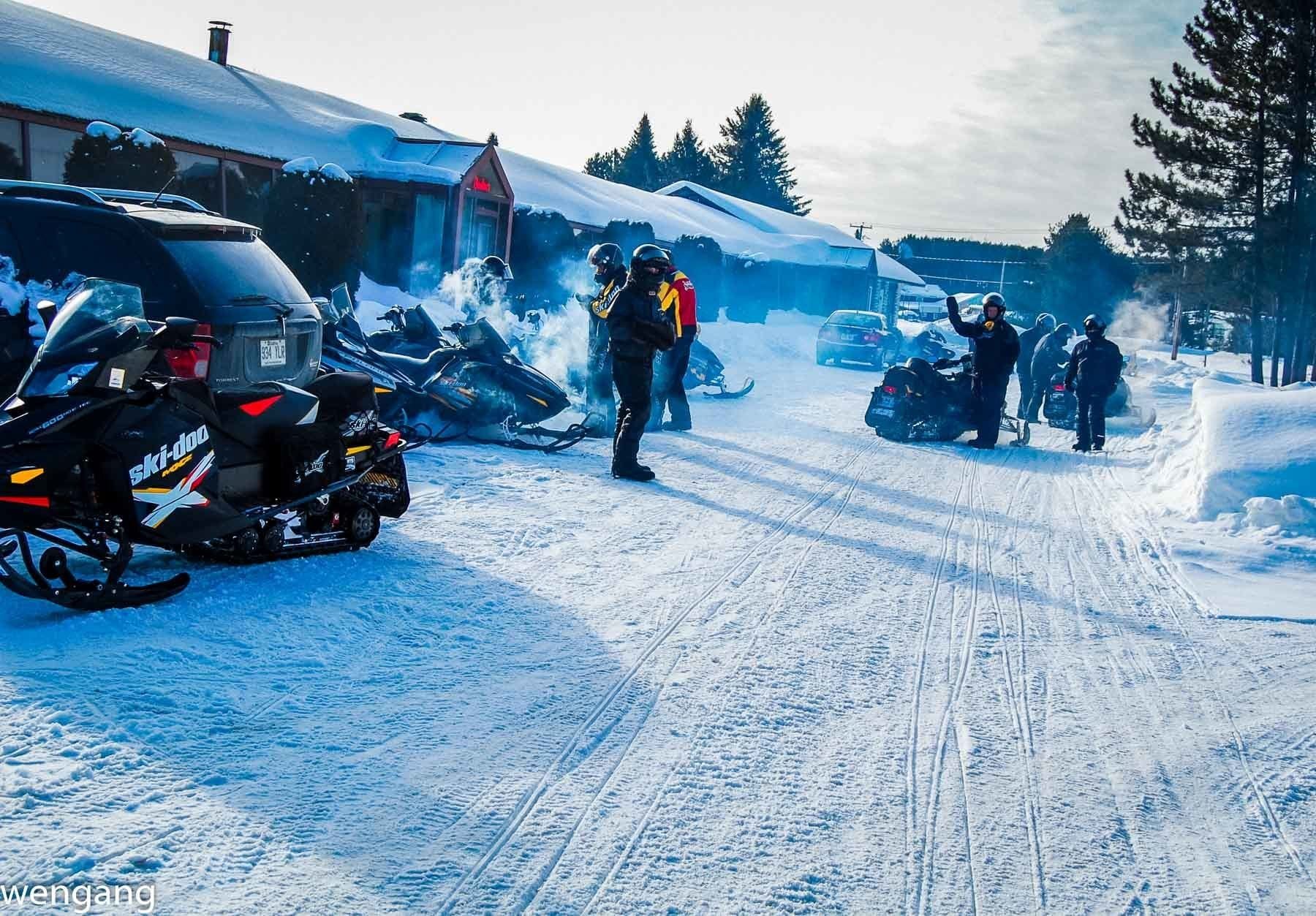 Una carretera cubierta de nieve con motos de nieve estacionadas al borde.