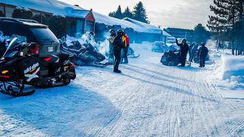 Una carretera cubierta de nieve con motos de nieve estacionadas al borde.