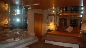 A hotel room with a bed, a small table, a mirror, and a window.