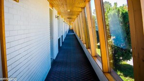 A corridor with white brick walls, wooden beams, and a patterned carpet.