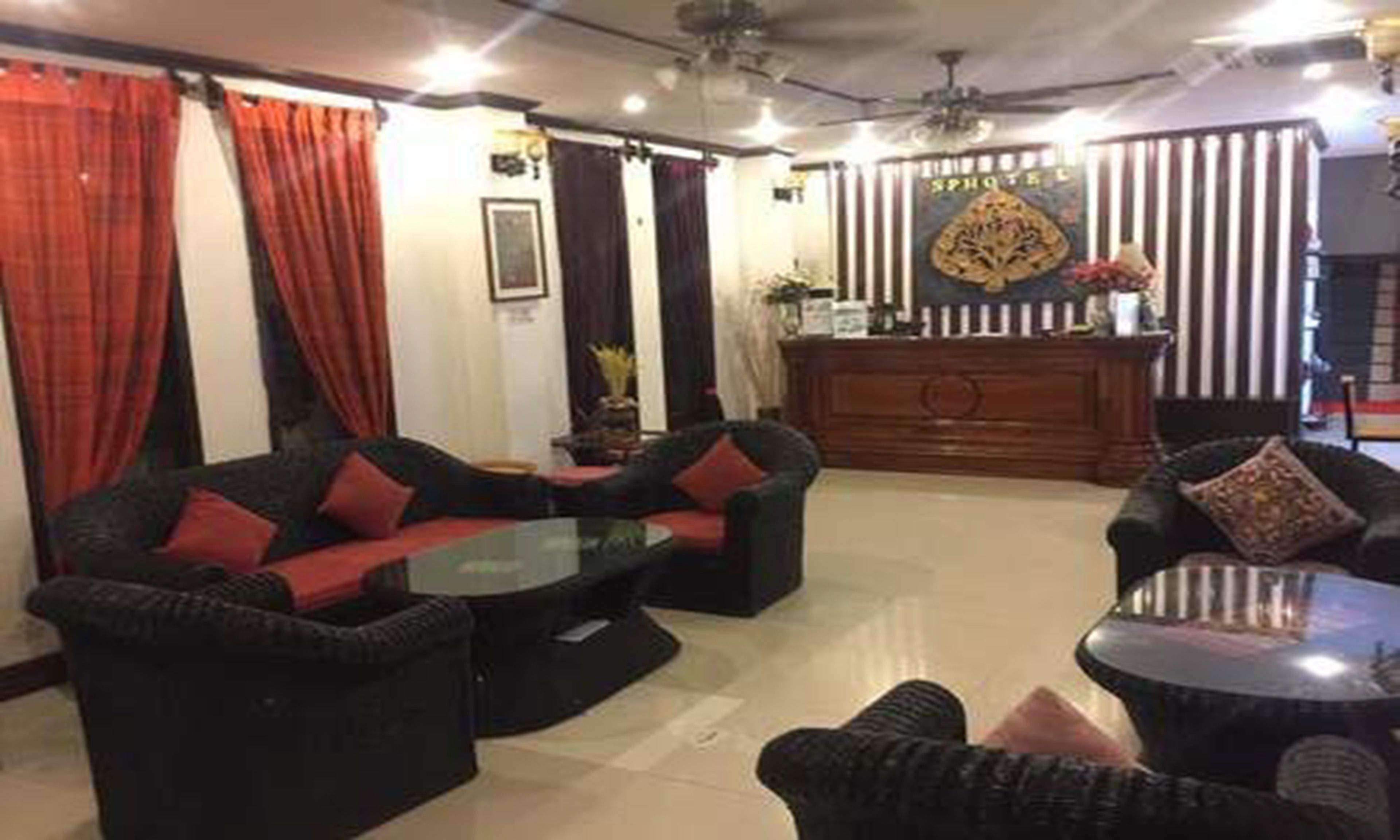 A hotel lobby with a reception desk, sofas, and a coffee table.