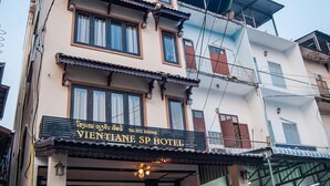 A multi-story building with a sign for "VIENTIANE SP HOTEL" at the ground level. There are steps leading to the entrance, and potted plants are placed in front. - Vientiane SP Hotel (Vientiane)