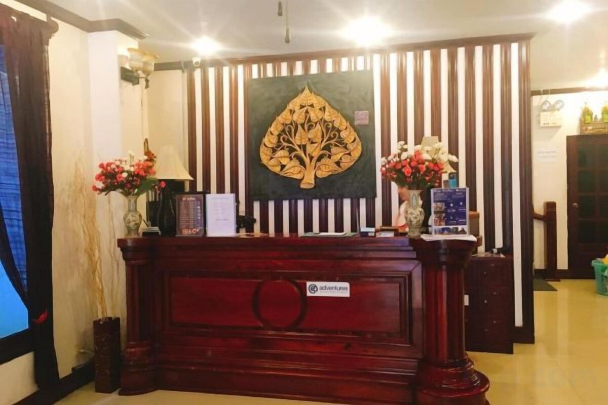 A reception desk with a decorative backdrop, a vase with flowers, and a sign with a logo.