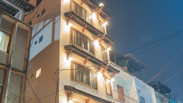A multi-story building with balconies, a sign indicating a hotel, and potted plants in front. - Vientiane SP Hotel (Vientiane)