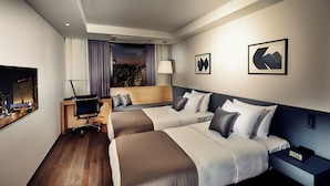 A hotel room with two beds, a desk, a chair, a nightstand, a lamp, and a city view. - Ramada by Wyndham Gunsan (Gunsan)