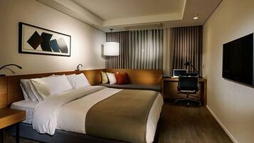 A hotel room with a bed, a desk, a chair, a TV, and a window with curtains.