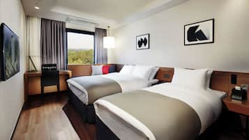 A hotel room with two beds, a desk, a chair, and a window with curtains.