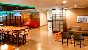 Un vestíbulo de hotel con un mostrador de recepción de madera, un sofá rojo y una zona de estar con sofás y sillones de cuero.