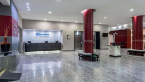 A modern reception area with a marble floor, red pillars, and a reception desk displaying the WYNDHAM logo.