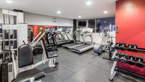 A gym with treadmills, weight machines, and dumbbells.