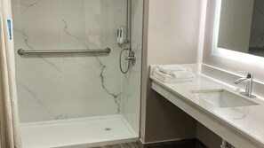 A bathroom with a shower, a sink, and a towel rack. - Studio 6 Suites Hot Springs, AR (Hot Springs)