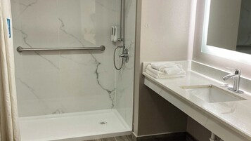 Un bagno con doccia, lavandino e portasciugamani.