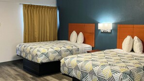 Habitación de hotel con dos camas, una ventana con cortina, un televisor montado en la pared y una mesita de noche.