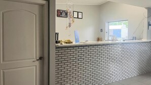 Un espace d’accueil avec un comptoir en briques, une porte et des certificats encadrés accrochés au mur.