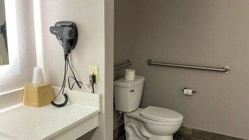 Un bagno con il water, un asciugamano ad aria, un dispenser di asciugamani e un erogatore di disinfettante per le mani sul mobile.