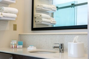 Et badeværelse med vask, spejl, håndklædestænger og toiletartikler.