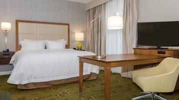 Habitació d'hotel amb llit, escriptori, cadira, televisió i làmpada.