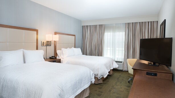 A hotel room with two beds, a TV, a desk, and a window with curtains. - Hampton Inn & Suites New Albany Columbus (New Albany)