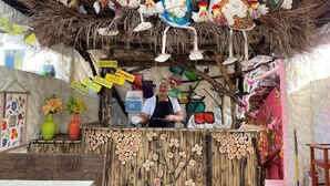A rustic food stall with a thatched roof, decorated with colorful chickens and signs indicating available food items. - Pousada das Galinhas (Ipojuca)