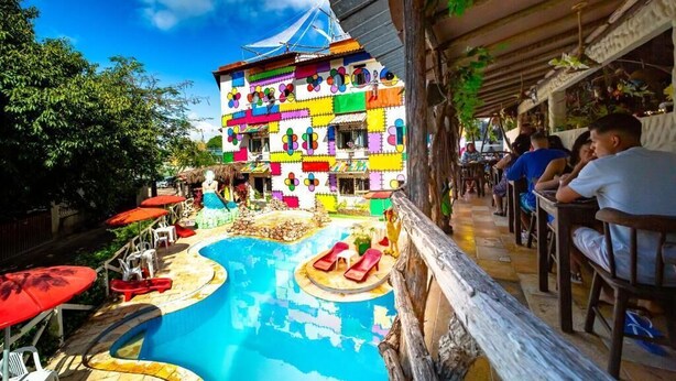 A colorful building with a pool and outdoor seating. - Pousada das Galinhas (Ipojuca)