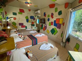 Quarto com duas camas, uma janela e uma parede decorada com formas geométricas coloridas.