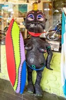 A statue of a person holding a surfboard in front of a shop window.