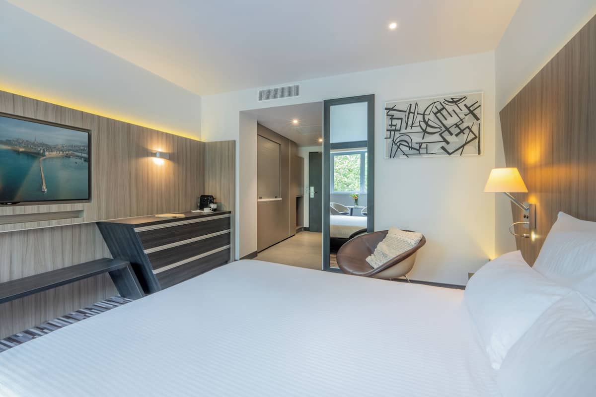 Una habitación de hotel moderna con una cama grande, un escritorio, una silla y un televisor.